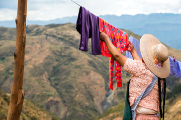 A woman hanging washing clothes on rope in the Andes mountain, Bolivia.