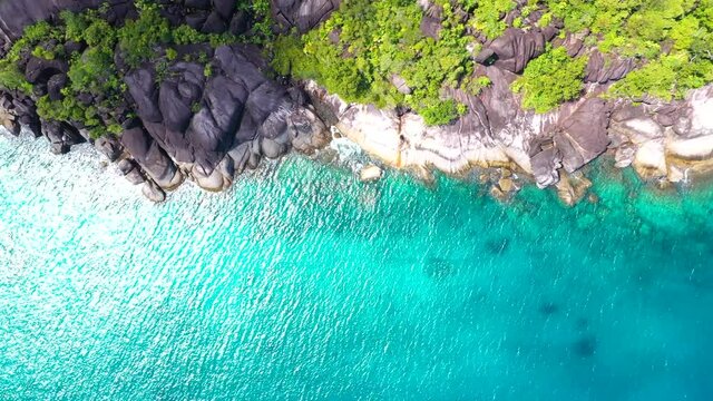 Drohnenclip an einem wundersch&ouml;nen Strand auf Mahe mit t&uuml;rkisblauem Wasser, Felsen und Palmen auf den Seychellen