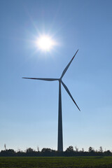 Wind turbine against background of blue sky and sun - 475539439