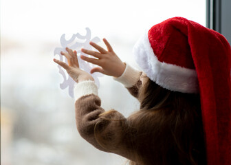 A cute little girl decorates the windows with snowflakes. New Year. Christmas. Atmosphere.