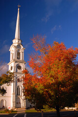 Autumn Colors and brilliant fall foliage compliment a traditional New England church with a tall steeple in Massachusetts