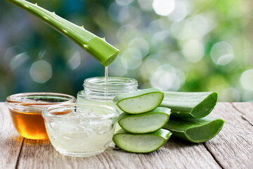 Aloe vera leaf with aloevera gel and honey on wooden table with green bokeh nature background. - obrazy, fototapety, plakaty