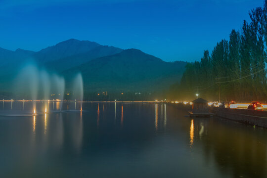Fountains over the Dal Lake with mountains in the background, at dusk. Dal Lake is the most famous lakes of Jammu and Kashmir, India and is important tourism attraction.