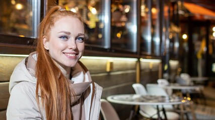 beautiful, long-haired, red-haired girl, drinking coffee, at a cafe, in the evening