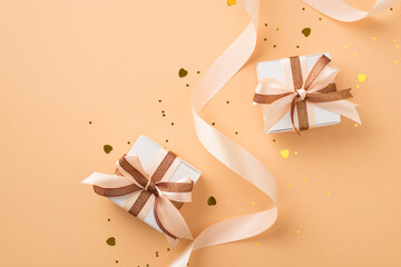 Top view photo of valentine's day decorations white gift boxes with glowing brown and light beige bows curly ribbon golden heart shaped confetti and sequins on isolated beige background with copyspace