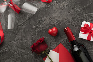 Top view photo of valentine's day decor wine bottle wineglasses giftbox with bow satin ribbon heart envelope with letter and red rose on isolated textured dark grey concrete background with copyspace