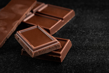 Pieces of milk chocolate on black background.
