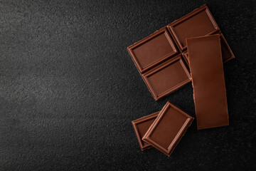 Pieces of milk chocolate on black background.