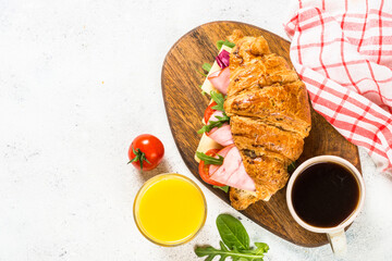 Croissant sandwich on white table.