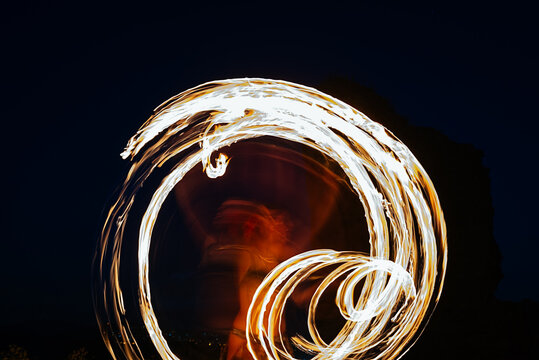 Faceless fire dancer with fire fan in darkness