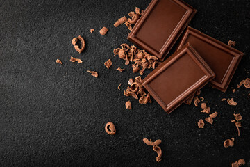 Pieces of milk chocolate on black background.
