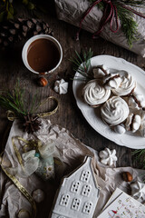 Holiday preparations. wrapping the presents. Meringue cookies with chocolate and almond cream ,cup of hot chocolate and natural winter decorations on old wooden table 
