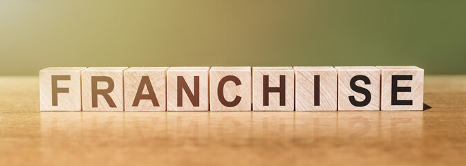 franchise word made with wooden blocks on a green-brown background