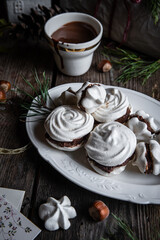 Meringue cookies with chocolate and almond cream and cup of hot chocolate, wrapped presents and natural winter decorations on old wooden table 