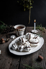 Meringue cookies with chocolate and almond cream and cup of hot chocolate, wrapped presents and natural winter decorations on old wooden table 
