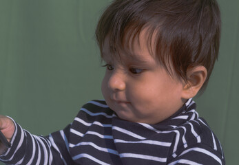 Baby looking at mobile phone. Sweet small baby with mobile phone on a isolated background. Head shot portrait. Front View. Close up. Indian ethnicity.