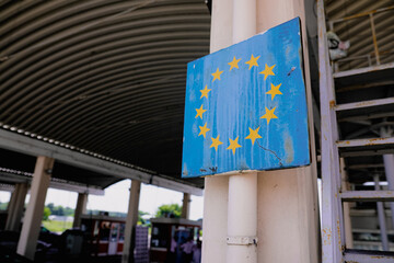 Shallow depth of field (selective focus) image with a worn out and rusty sign at the Romanian border with the European Union symbol. - obrazy, fototapety, plakaty