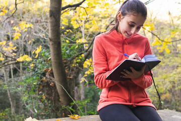 happy woman writing in notebook in nature