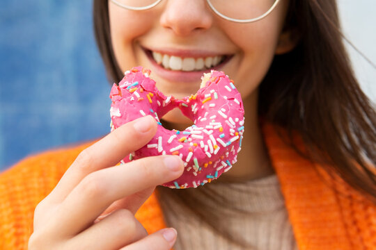 Anonymous female eating delicious sprinkled donut