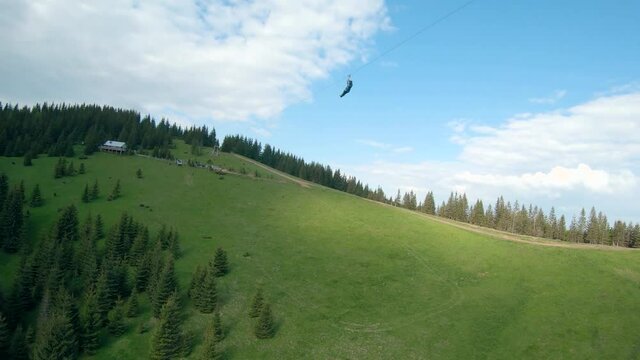 Unusual view of a woman riding a zip line among the mountains. Fast and maneuverable flight around a person. Filmed on FPV drone.