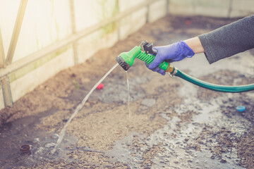 Hand in glove holds watering hose/hand in a blue glove holds a green watering hose.