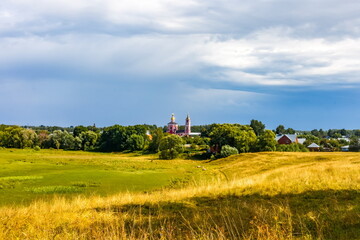 Obraz premium Summer landscape with buildings, churches, trees, shrubs, grass, sky with clouds of the city of Suzdal in Russia