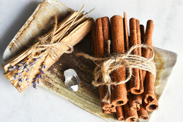 A top view image of smudge sticks and cinnamon with clear crystal point on a hand made pottery...