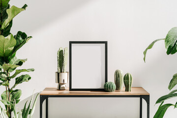 Houseplants and mockup picture frame on table in living room