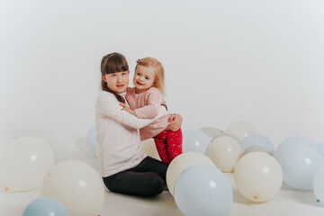 sisters playing with balloons on the white background 