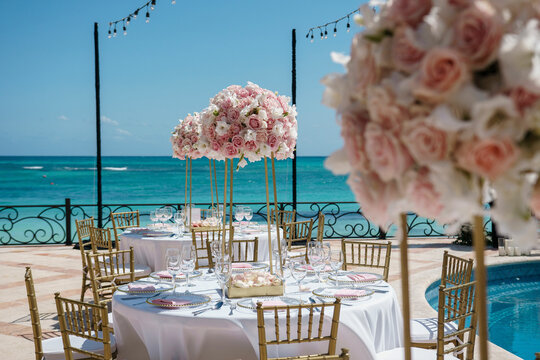 Wedding near the sea Pink roses bouquet stands on the tables Wedding table set Sea view background Beach wedding venue Decorated table for a wedding reception at the beach resort Cropped photo