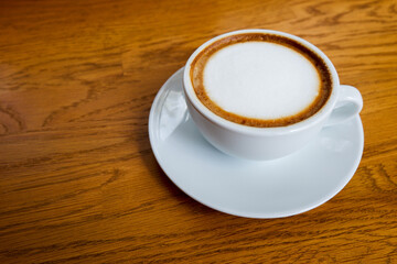 hot coffee in white ceramic cup on white ceramic plate, on wooden floor background, food, drink, copy space