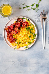 Traditional breakfast scrambled eggs with fried bacon