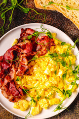 Traditional breakfast scrambled eggs with fried bacon