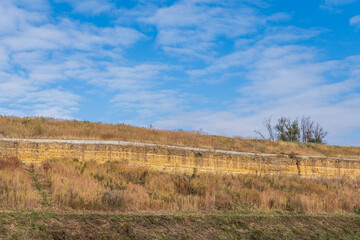 hill with yellow autumn grass under the bright blue sky with clouds backgrounds