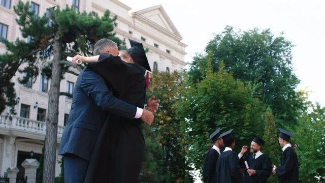 Happy and excited beautiful lady at her graduation running and hugging hard his dad after she was graduate with diploma she wearing a graduation cap and suit. ARRI Alexa Mini.
