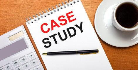 On a wooden table there is a white calculator, a white cup of coffee, a pen and a white notebook with the text CASE STUDY. Business concept