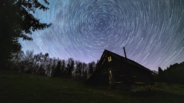 Startrail, Milky way galaxy star trails rotates over old wooden hut in night sky forest nature Astronomy Time lapse 4K