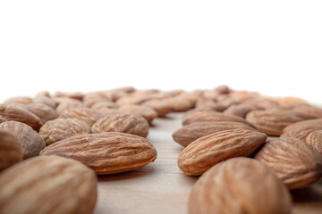 Group of almond nuts seeds in extreme close-up with short field of focus blurred in perspective. Nutrition, vitamins for vegetarians. Copy space