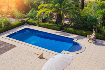 A modern pool in the garden with palm trees for relaxation of tourists near the hotel. Top view, summer, rocking chair.