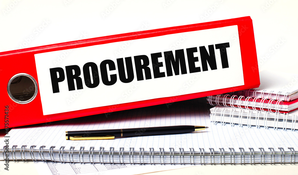Poster on the desktop are notebooks, a pen and a red folder for papers with the text procurement business c