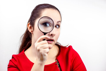 Young attractive woman with magnifying glass in her hand near the eye. Inspection, discovery, research, surprise, curiosity concept.