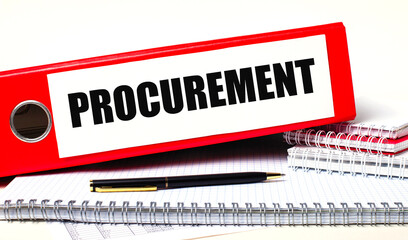 On the desktop are notebooks, a pen and a red folder for papers with the text PROCUREMENT Business...
