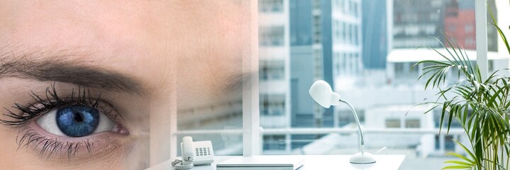Composite image of close up of a female eye and office interior