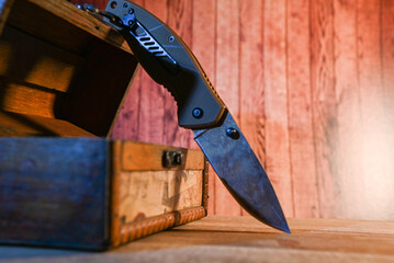sharp knife on wooden background with vintage jewelry box