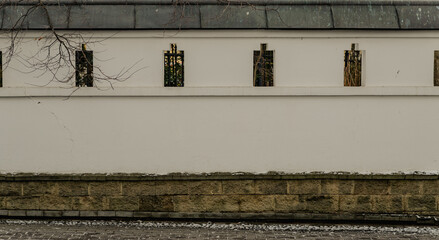 Old medieval stone wall fence defensive structure with small windows loopholes