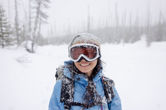 Portrait happy woman in goggles in snowy winter woods
