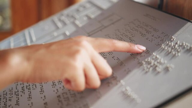 Touching letters on sheet of paper close-up, blindman reading braille book using his fingers, poorly seeing person learning to read, disabled people concept