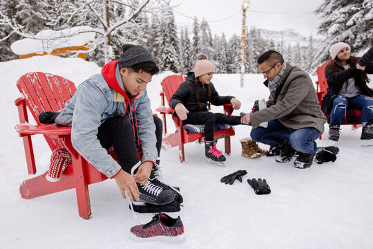 Family putting on ice skates in snow