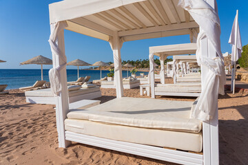 Fototapeta na wymiar White sun canopy with mattress on luxury sand beach in tropical resort in Red Sea coast in Egypt, Africa