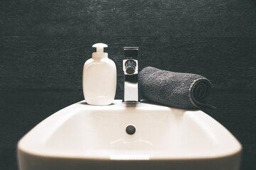 Closeup view of a bidet with rolled up towel, soap dispenser. Modern environment bathroom fixtures...